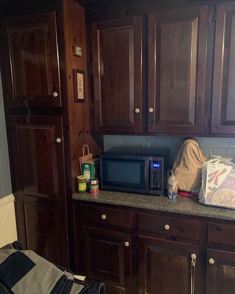 A kitchen with wooden cabinets and a microwave on the counter