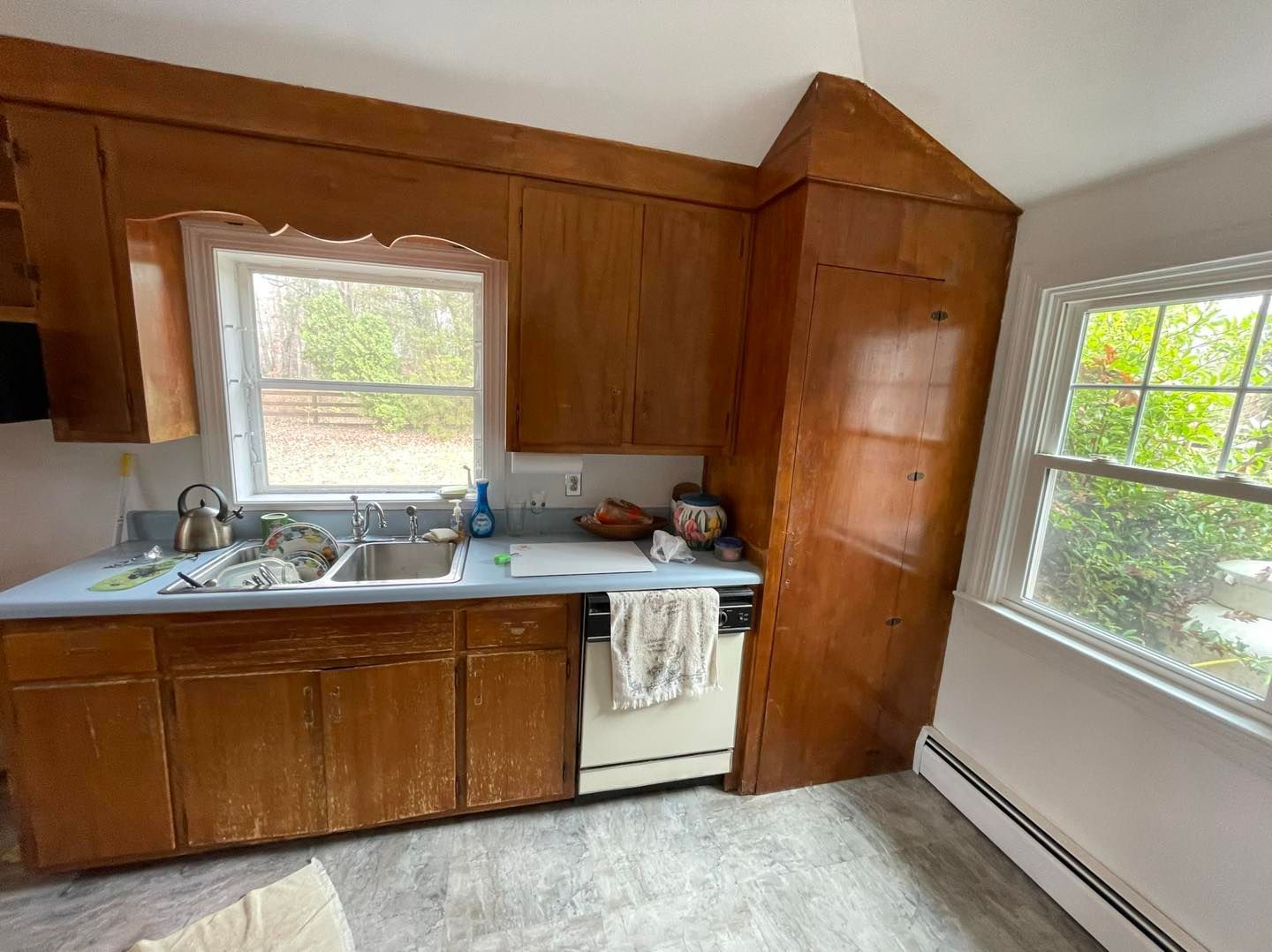 A kitchen with wooden cabinets , a sink , and a window.