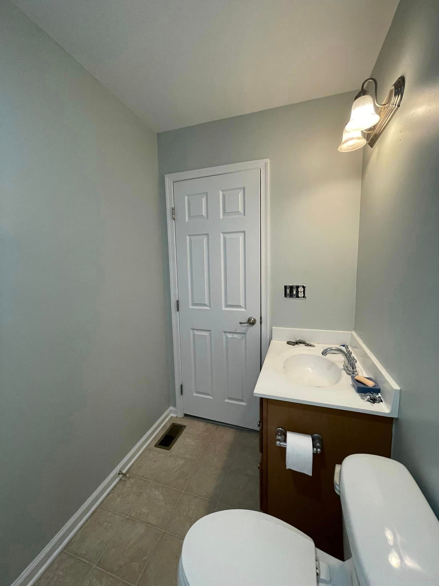 A bathroom with a toilet , sink , and door.