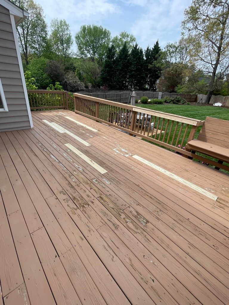 A wooden deck with a bench and a fence in the backyard of a house.