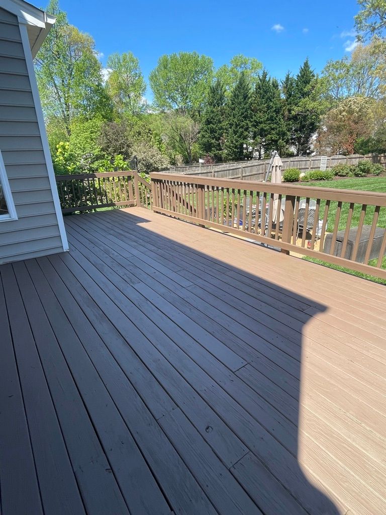 A wooden deck with a railing and trees in the background