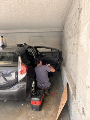 A man is working on the inside of a car in a garage.