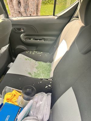 The back seat of a car with a lot of trash on it.