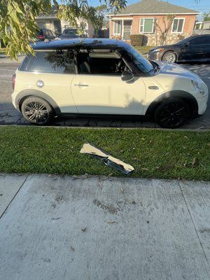 A white mini cooper is parked on the side of the road.