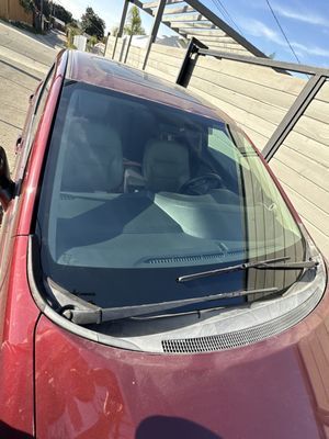 A red car with a windshield wiper is parked in a parking lot.