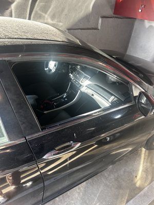 A black car is parked in a garage next to stairs.