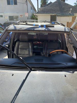 A car with a broken windshield is parked in front of a house.