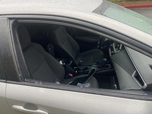 A car with a broken window is parked in a parking lot.
