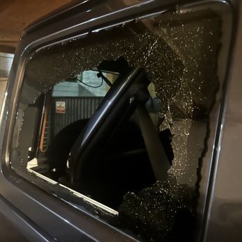 A car with a broken window and a sign that says no parking