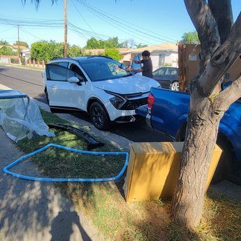 A white suv is parked on the side of the road next to a tree.