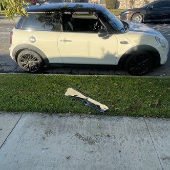 A white mini cooper is parked on the side of the road.