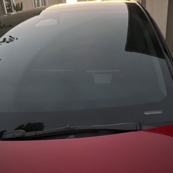A close up of a red car 's windshield and hood