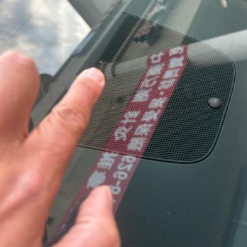 A close up of a person 's finger pointing at a sticker on a car windshield