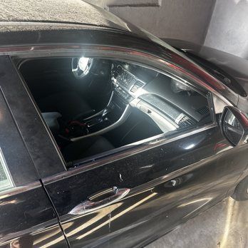 A black car is parked in a garage with the door open.