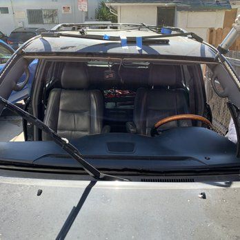 A car with a broken windshield is parked in front of a house.