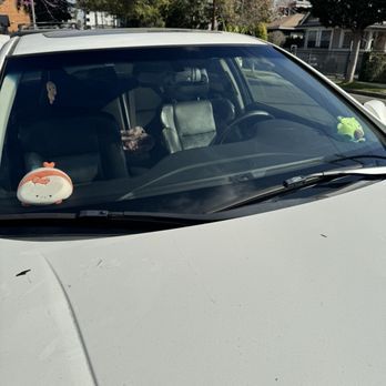 A white car with a stuffed animal on the windshield.