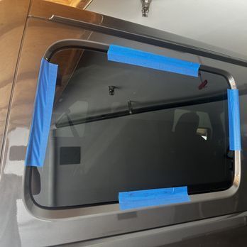 A close up of a car window with blue tape on it.
