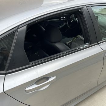 A silver car is parked in a parking lot with the door open.