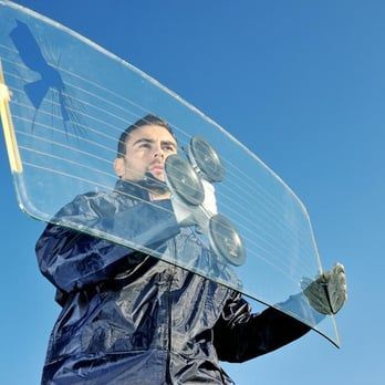 A man is holding a windshield with suction cups on it.
