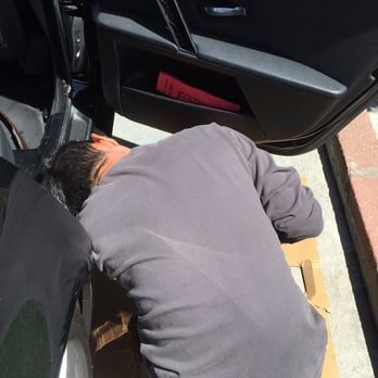 A man laying on the ground next to a car