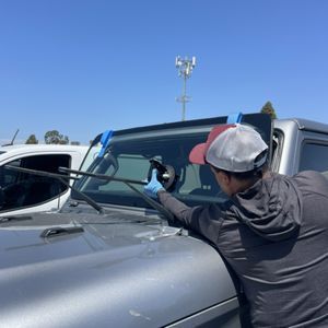A man is fixing a windshield on a silver truck
