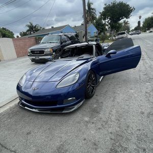 A blue sports car is parked on the side of the road with its doors open.