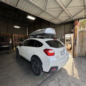 A white suv with a roof rack is parked in a garage.