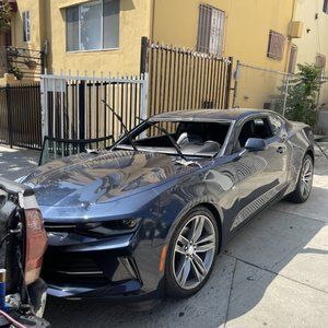 A blue car is parked on the side of the road in front of a building.