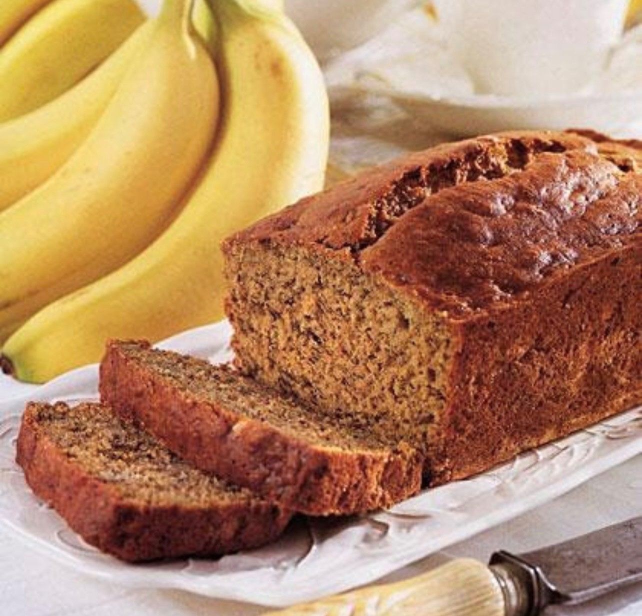 A loaf of banana bread is sitting on a white plate