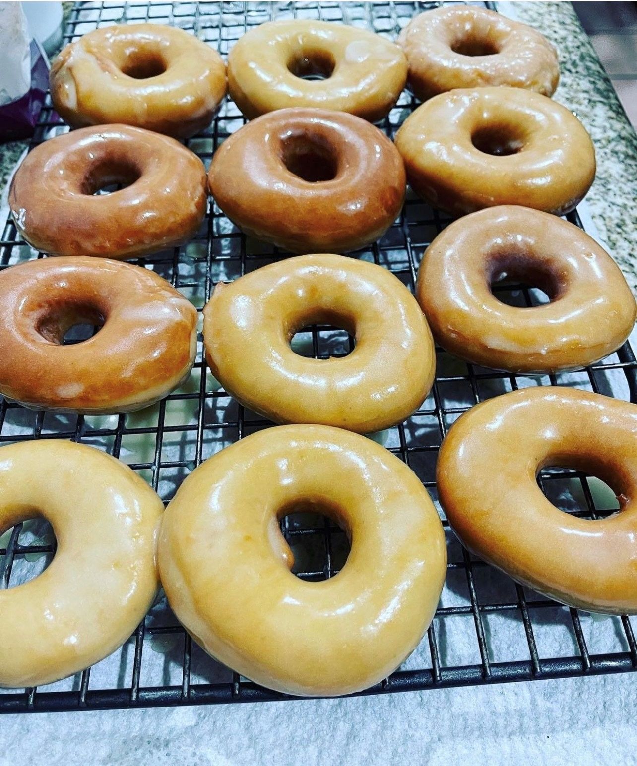 A bunch of glazed donuts are sitting on a cooling rack