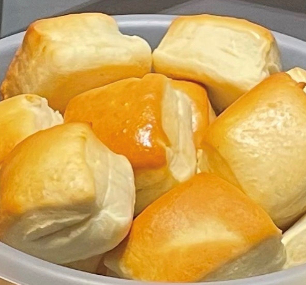A white bowl filled with a bunch of rolls