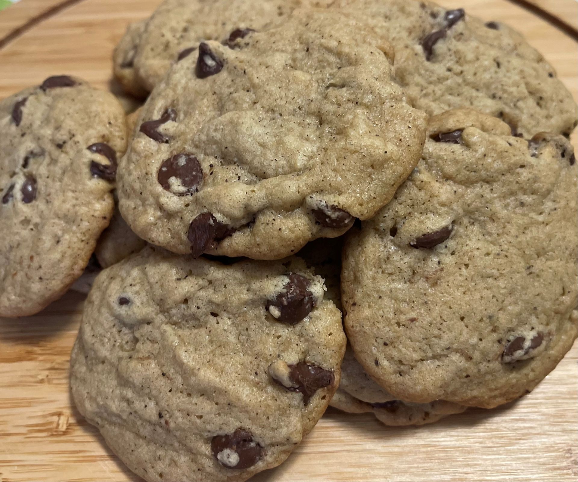 A pile of chocolate chip cookies on a wooden plate