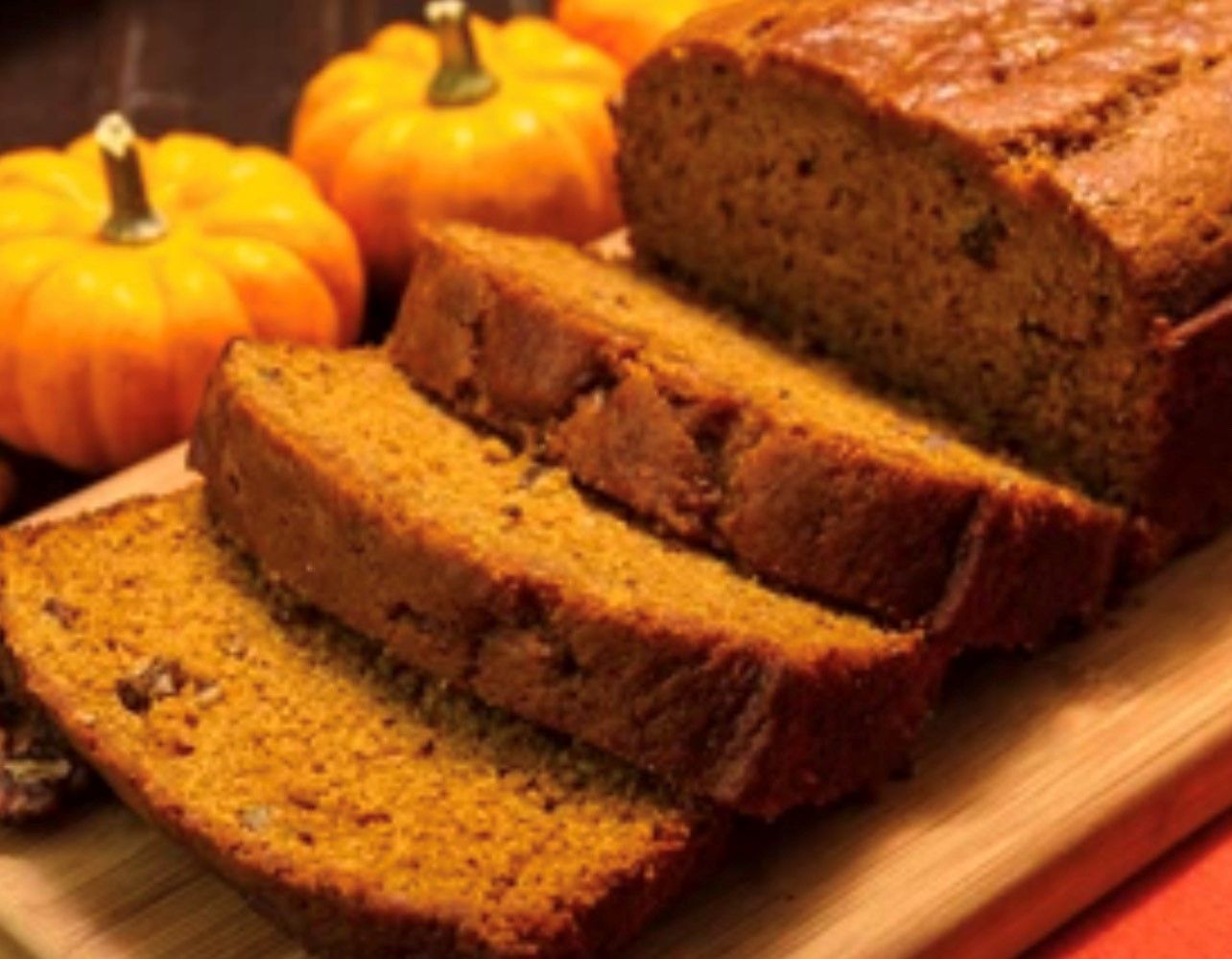 A loaf of pumpkin bread is sitting on a wooden cutting board