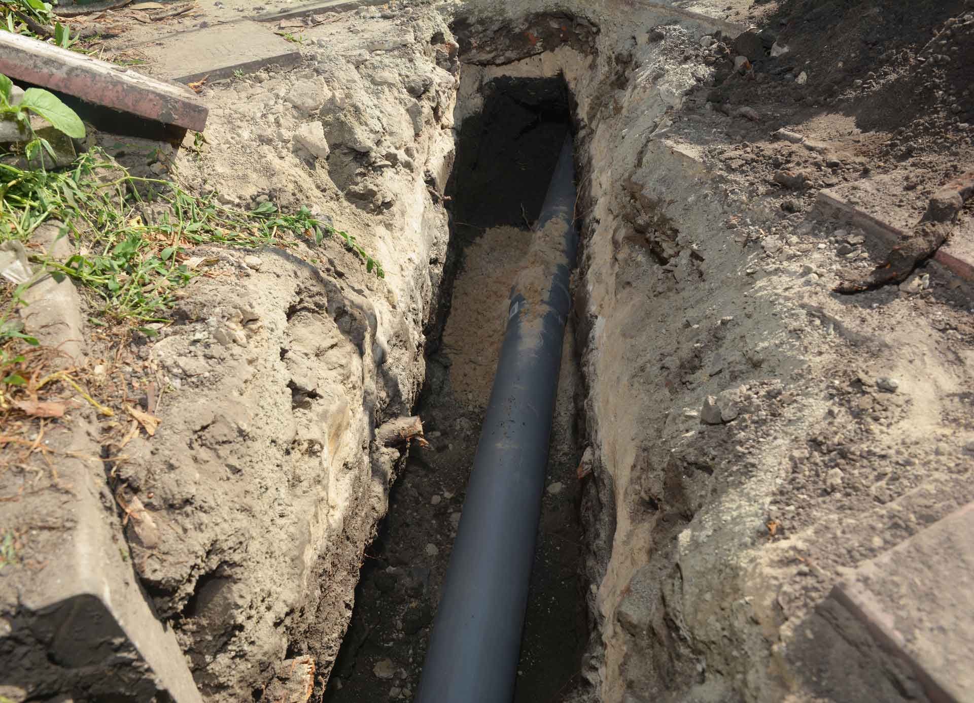 Sewer pipe in the ground trench. House sewer drain line repair.
