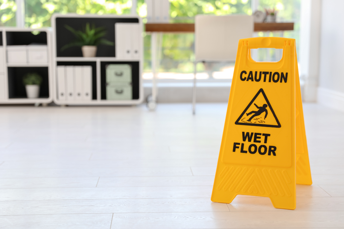 A yellow caution wet floor sign is sitting on the floor in an office.
