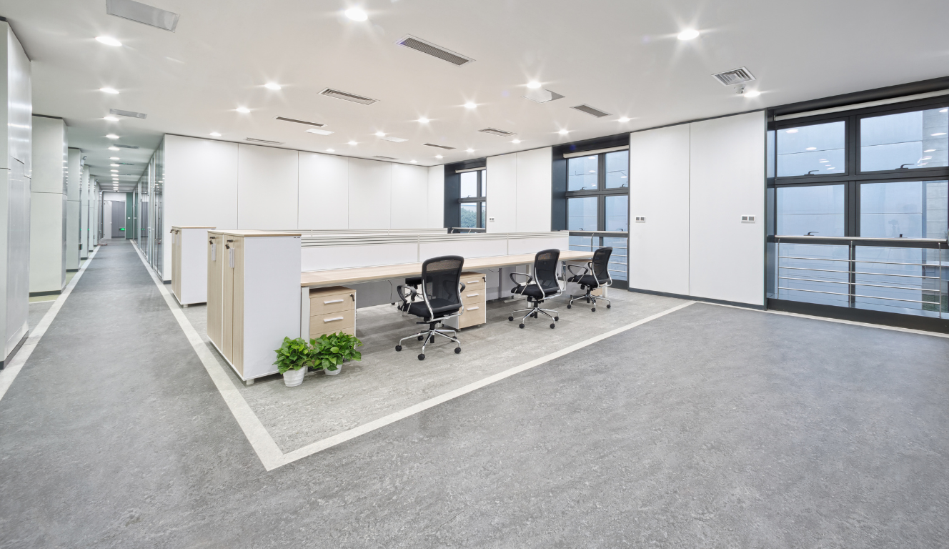 An empty office with a long hallway and a row of desks and chairs.