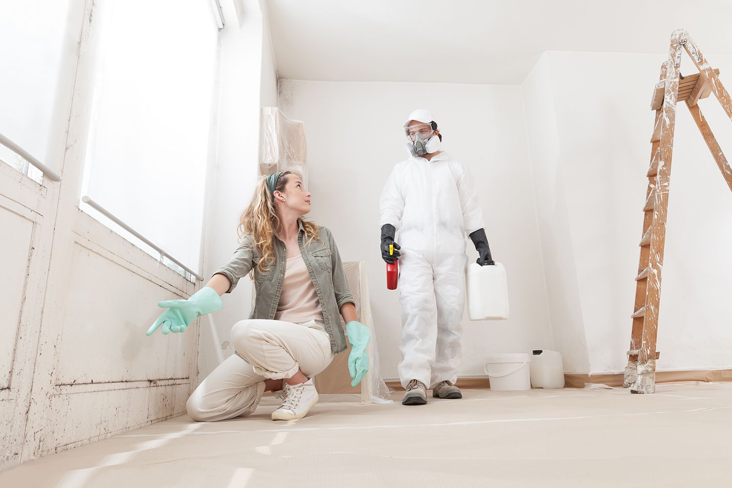 A concerned woman shows a mold problem to a professional for remediation treatment.