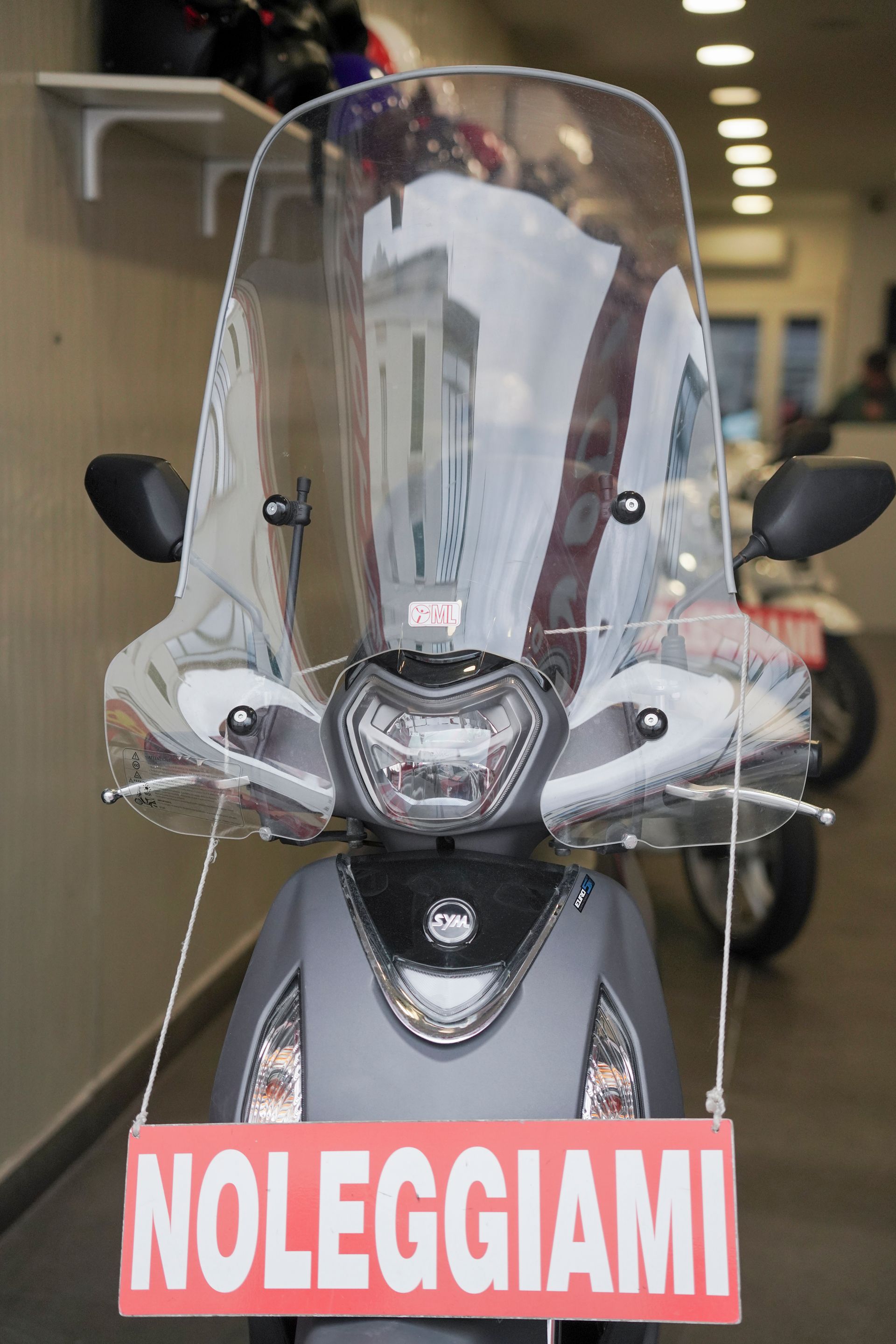 Uno scooter con parabrezza e cartello con scritto noleggiami