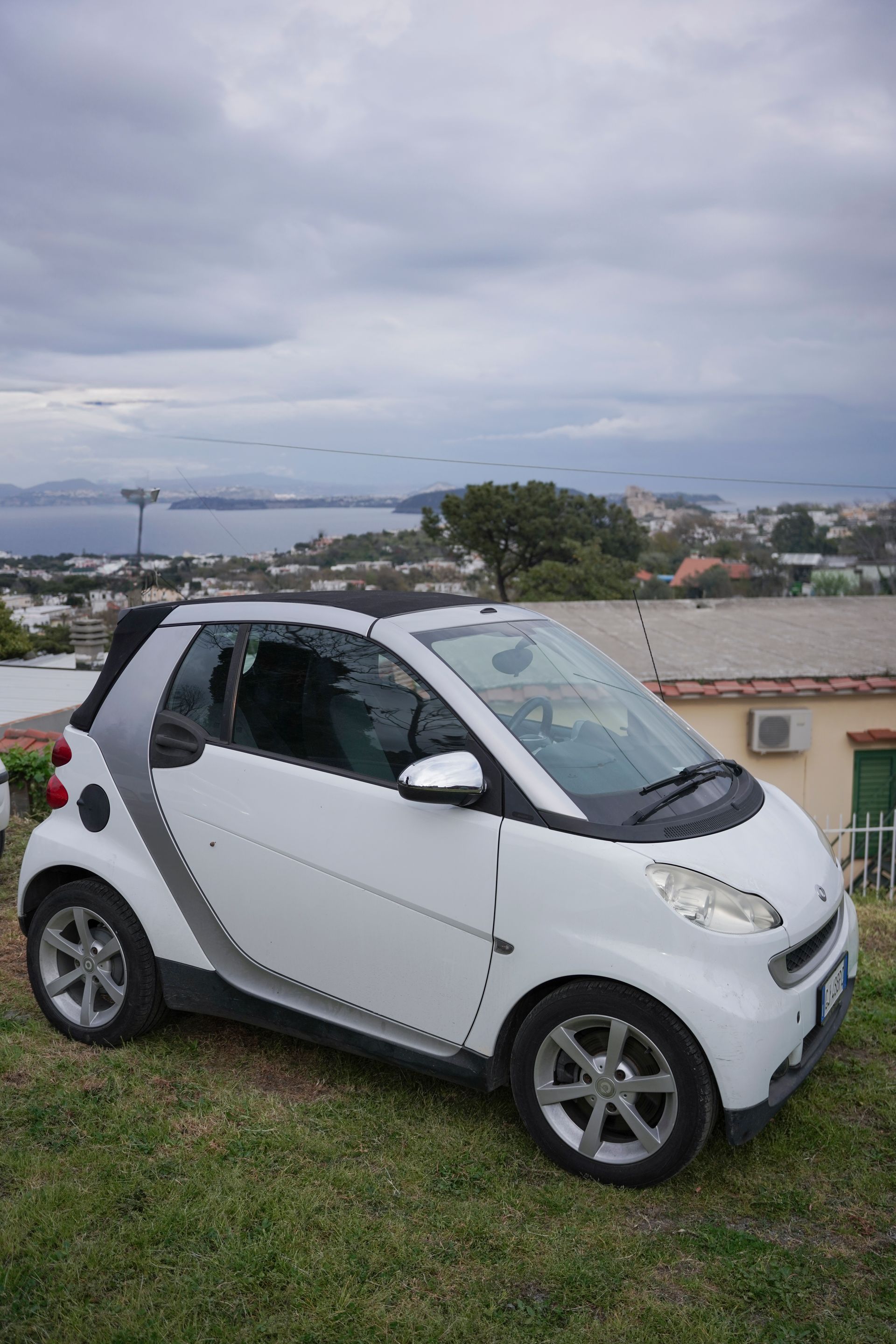 Una piccola automobile bianca è parcheggiata in un campo erboso.