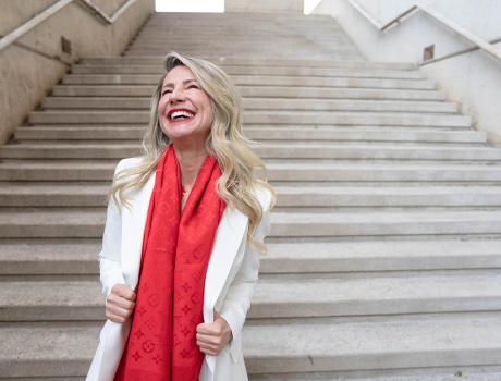 A woman wearing a red scarf and a white jacket is standing on a set of stairs.