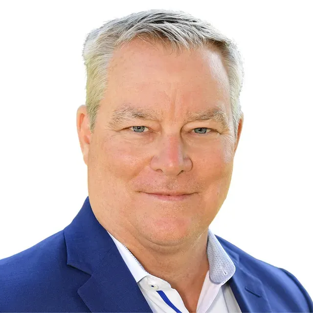 A man in a blue suit and white shirt is smiling for the camera