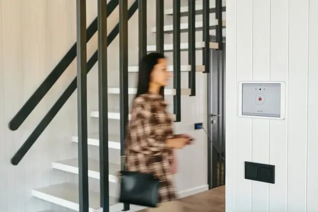 A woman is walking down a set of stairs in a house.