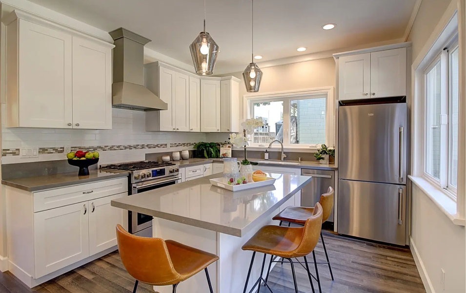 A kitchen with white cabinets , stainless steel appliances , and a large island.