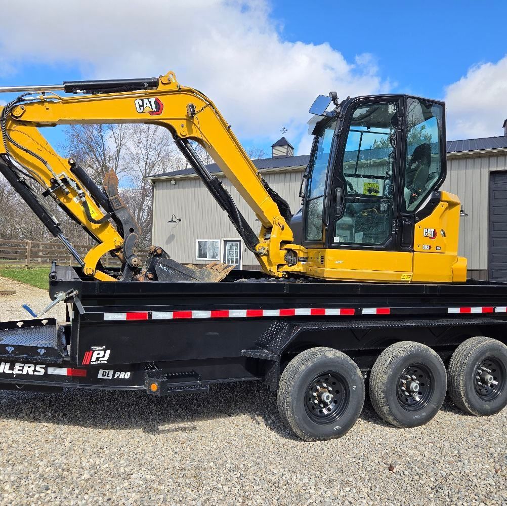 A yellow cat excavator is parked on a trailer