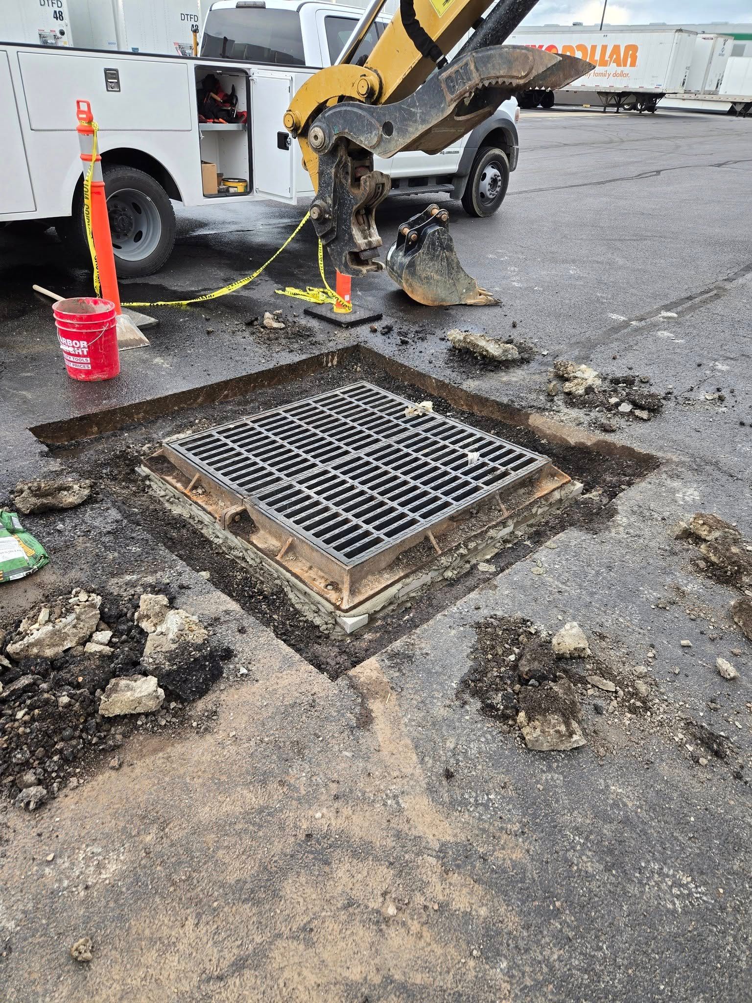A manhole cover is being removed from the ground in a parking lot.