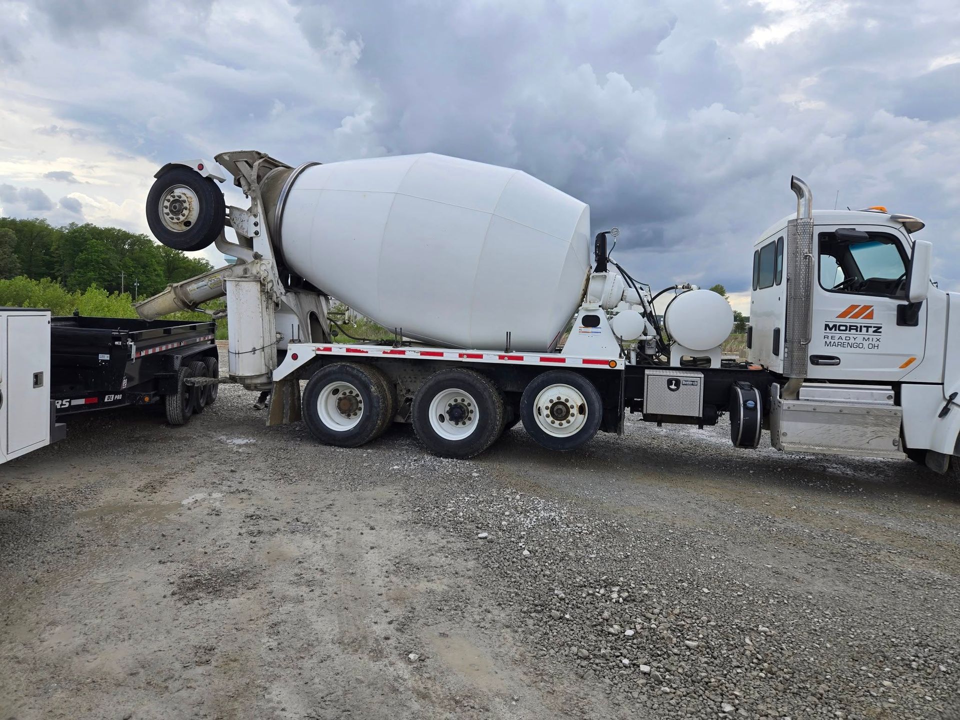 A concrete mixer truck is parked in a gravel lot.