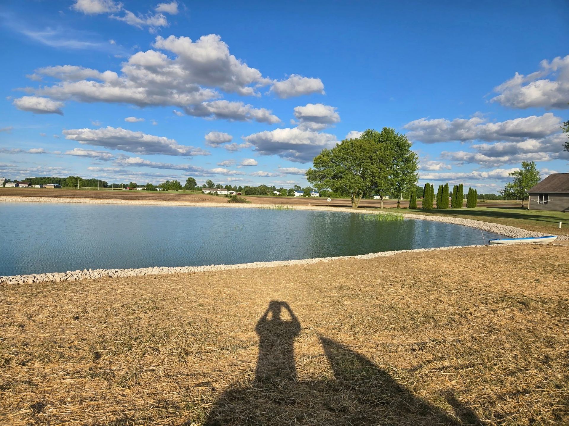 A shadow of a person taking a picture of a lake