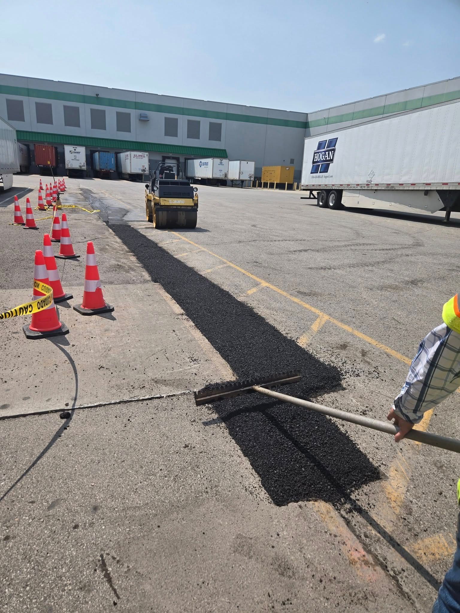 A man is holding a shovel in a parking lot in front of a warehouse.