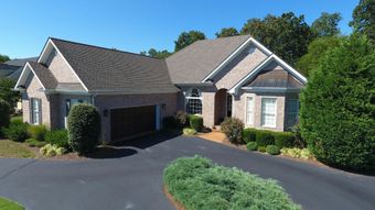 An aerial view of a large brick house with a driveway leading to it.