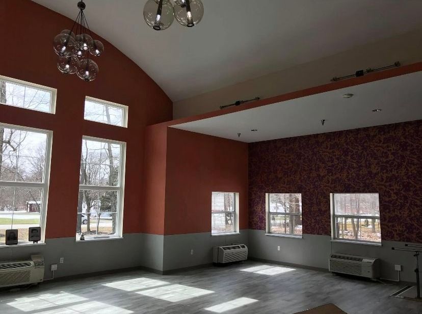 Interior of a room with orange walls and windows. Gray bottom half of walls, patterned accent wall.